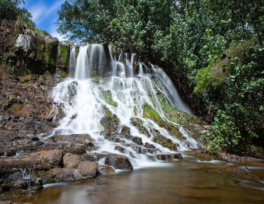 Fine art photograph of Hoopii Falls on Kauai. The water  rolls down a stepped cliff side to create an idyllic small waterfall and shallow pool. Landscape photography by Inspiring Images Hawaii.