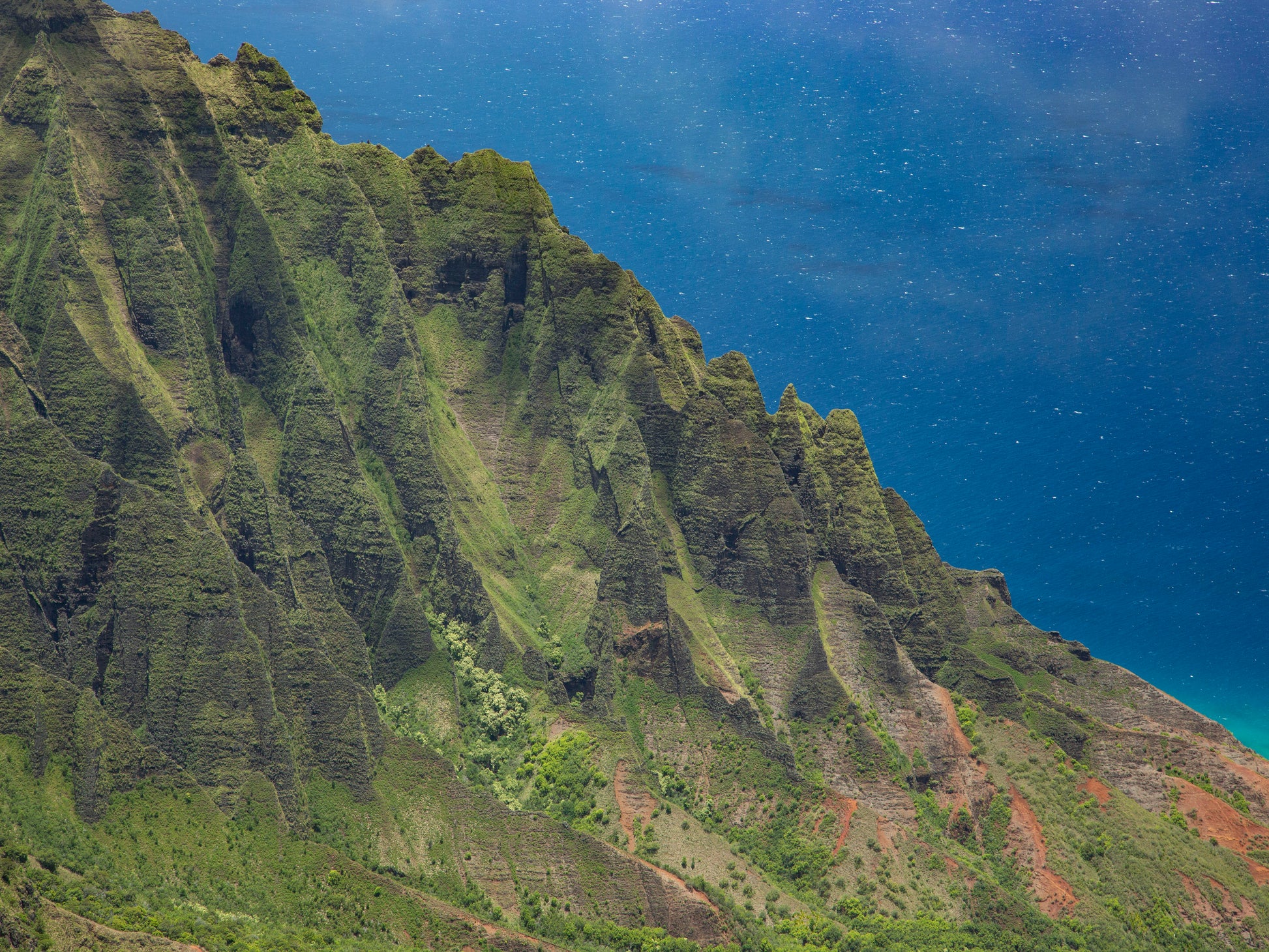 Fine art photograph of the cliffs that frame Kalalau Valley on Kauai’s Napali Coast. The steep green cliffs contrast with the deep blue ocean in the background. Landscape photograph by Inspiring Images Hawaii.