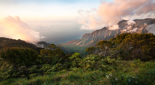 Fine art photograph of Kauai’s Kalalau Valley, taken at sunset. Pink hued clouds and rugged cliffs frame the valley with a calm ocean in the background. Landscape photography by Inspiring Images Hawaii.