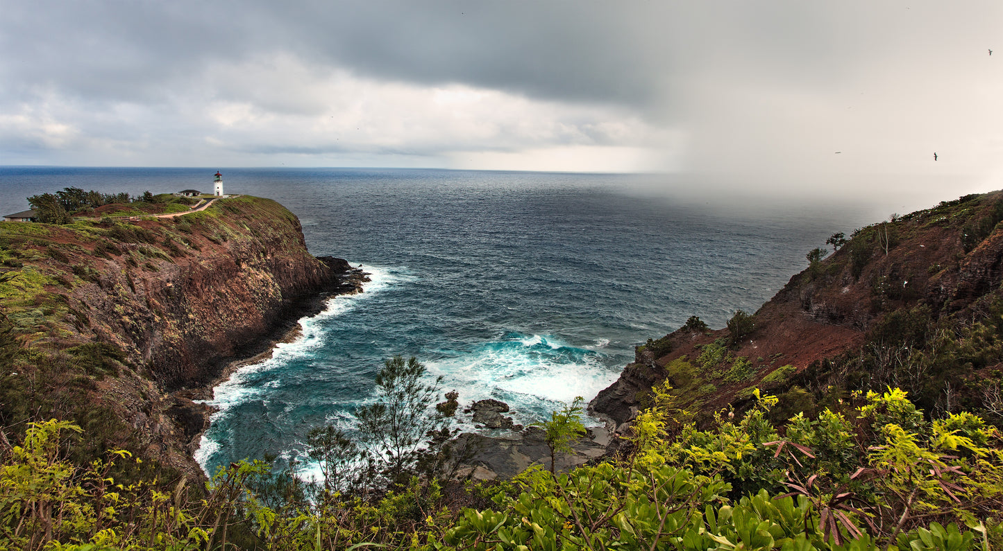 A fine art photograph of a rainstorm approaching Kilauea Lighthouse, set on a rocky outcropping in Kauai’s sea bird sanctuary. Outdoor landscape photography by Inspiring Images Hawaii.