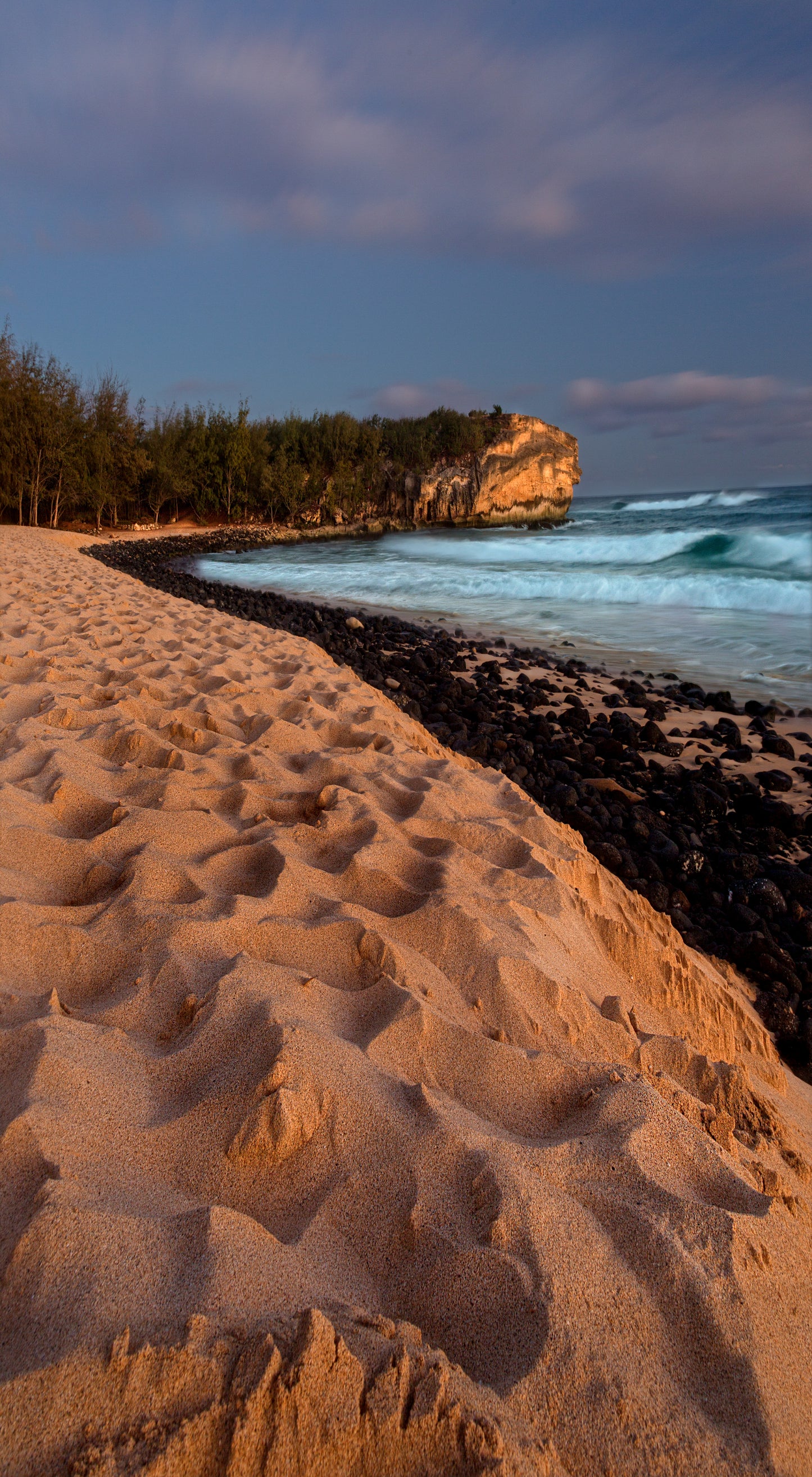 Fine art photograph of Kauai’s Shipwrecks Beach and cliff at sunset. By outdoor and landscape photographers Inspiring Images Hawaii.
