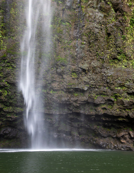A close up fine art photograph of Kauai’s Hanakapi’ai Falls. The falls cascade into a deep emerald pool next to a moss covered cliff. Landscape photography by Inspiring Images Hawaii.